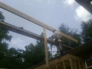 Carpenter setting a ridge beam over a new addition frame — Ice Dam Removal by Roofing Brothers in Watson