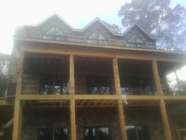 Dormers and porch framing on a large log home under construction — Roof Coating work by our crew in Watson