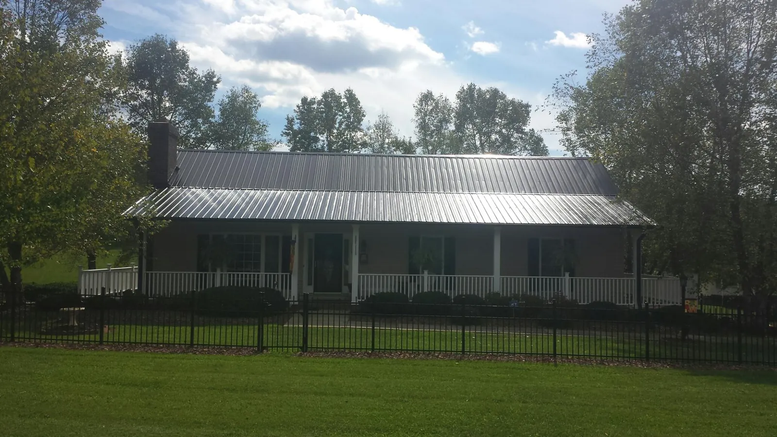 Gray metal roof on a brick ranch with a full width front porch — Gutter Guard Installation work by our crew in Watson