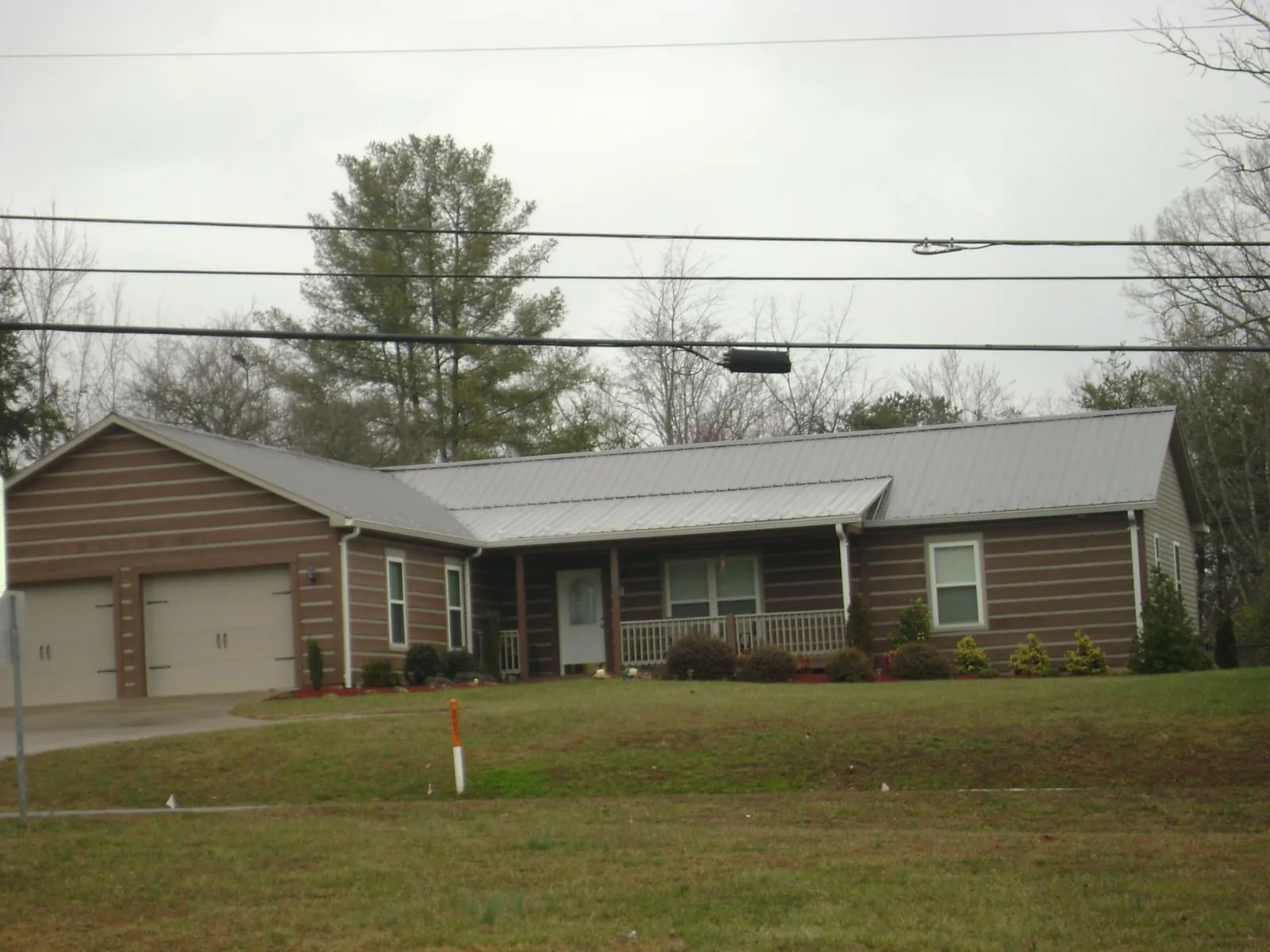 Gray metal roof on a log sided ranch home with a front porch in Watson