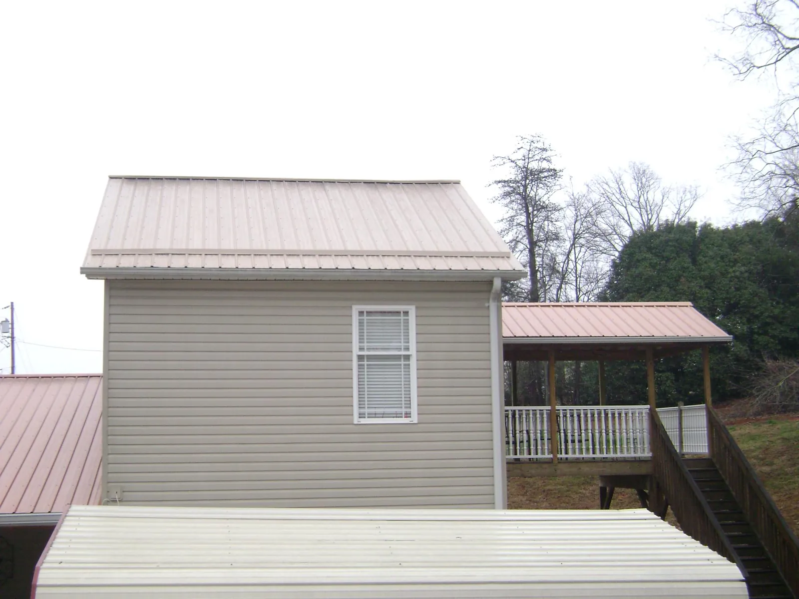 Tan metal roofs on a two story addition and attached porch, from a Roof Replacement job in Watson
