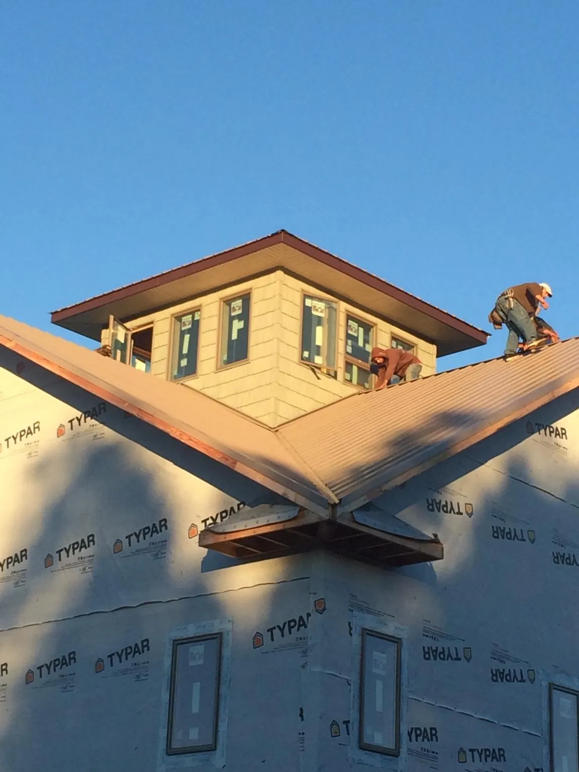Roofers working around a rooftop cupola on a new metal roof at sunset — Roof Waterproofing in Watson by Roofing Brothers